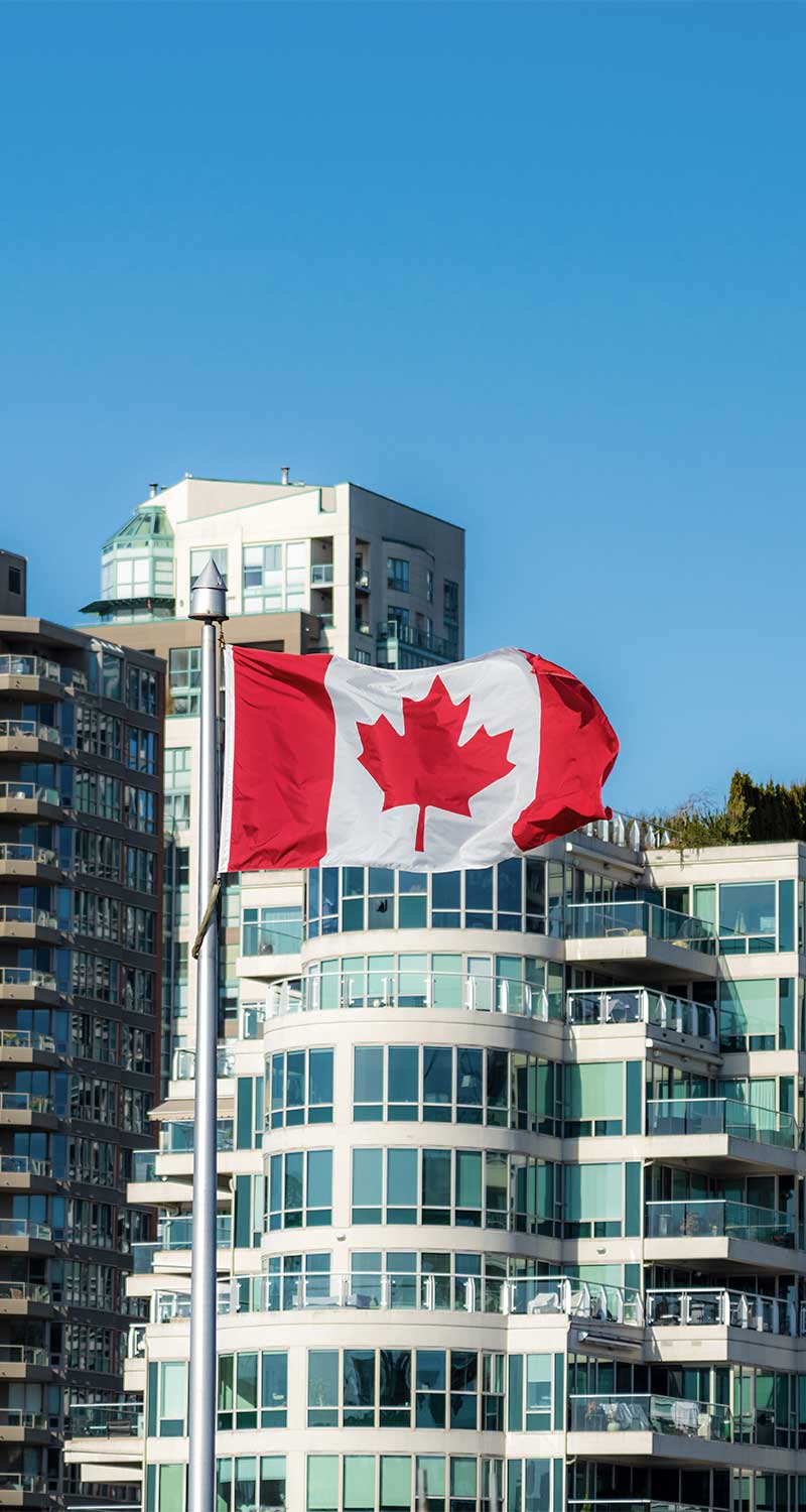Canadian flag waving in front of modern city buildings in Vancouver
