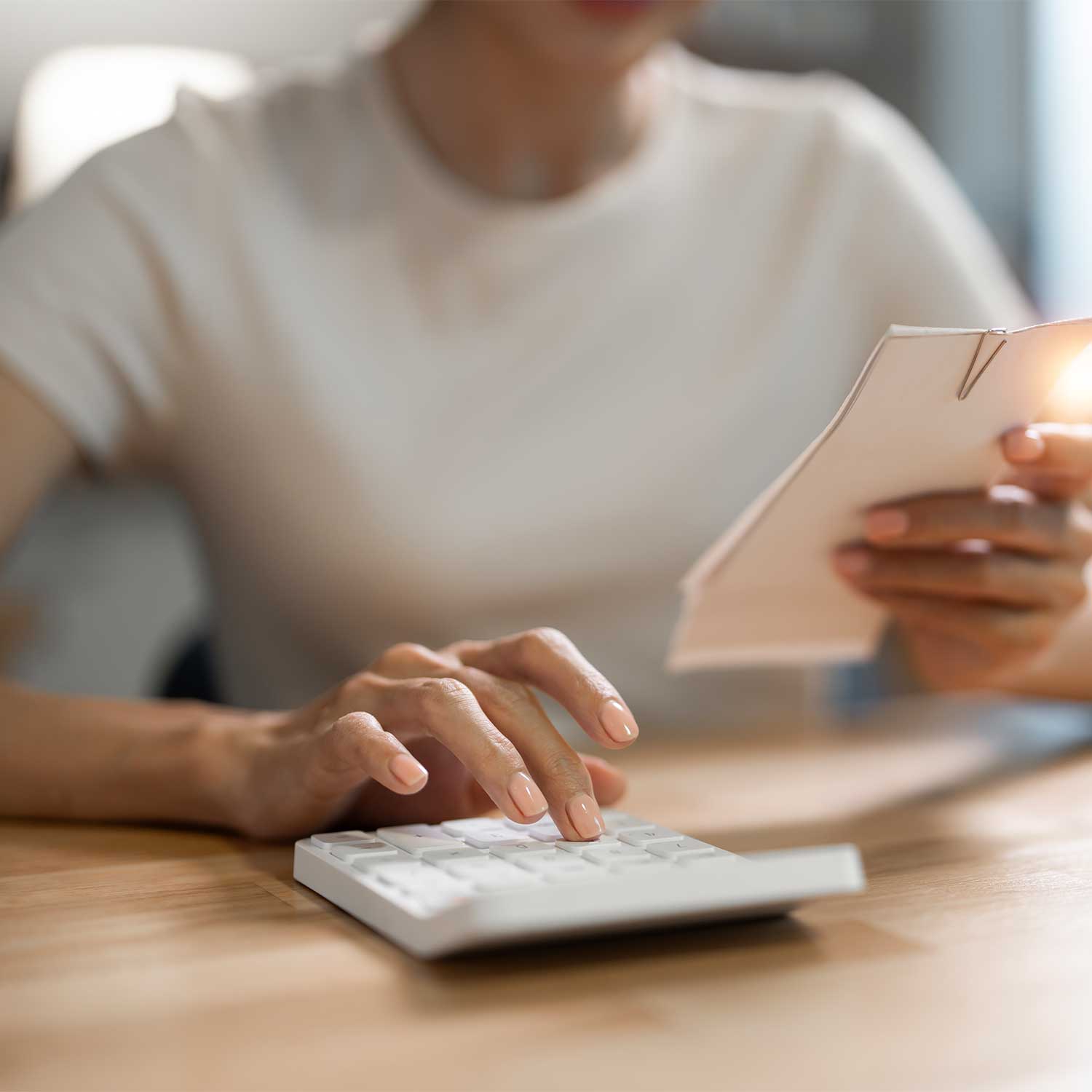 Person calculating expenses with calculator and reviewing bills at home