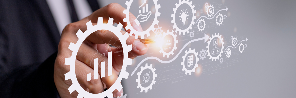A person in a suit reaches forward to interact with a digital interface of interconnected gears and icons, symbolizing business processes, data analytics, and system integration.